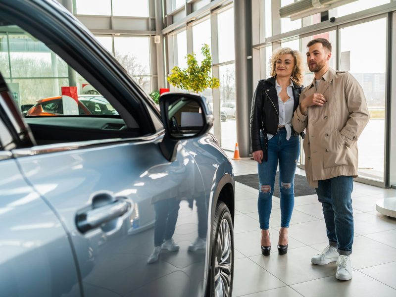 Beautiful couple in car dealership chooses car