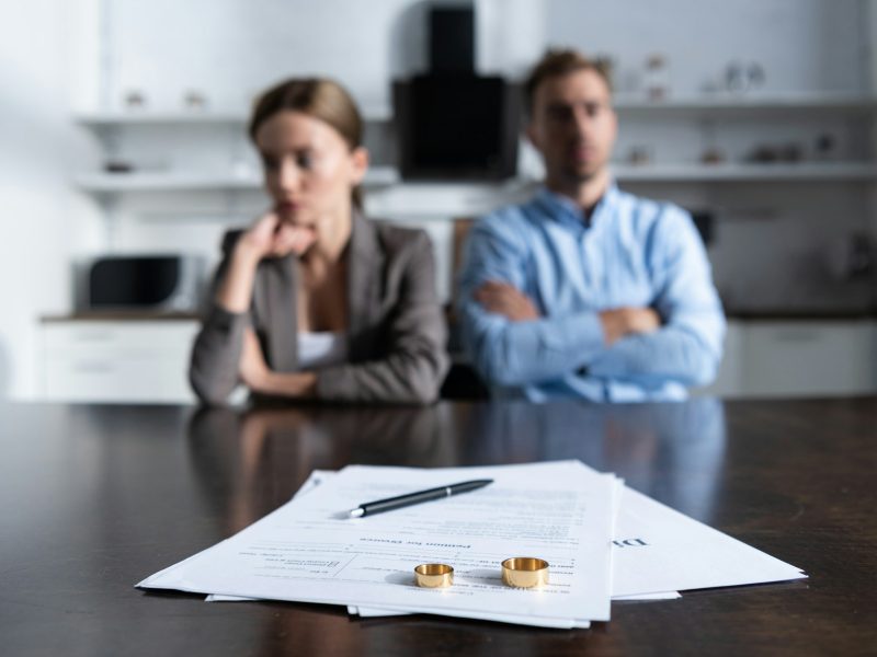 selective focus of couple sitting at table with divorce documents